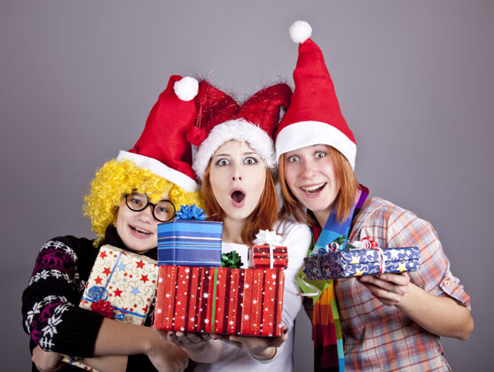 女人三个戴着滑稽帽子过圣诞节的女朋友礼品工作室射击甜蜜女孩女性