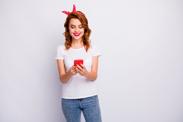 情绪正面开朗女性写真博客使用手机阅读社交媒体新闻穿t恤隔离白色墙壁手机卷发成熟