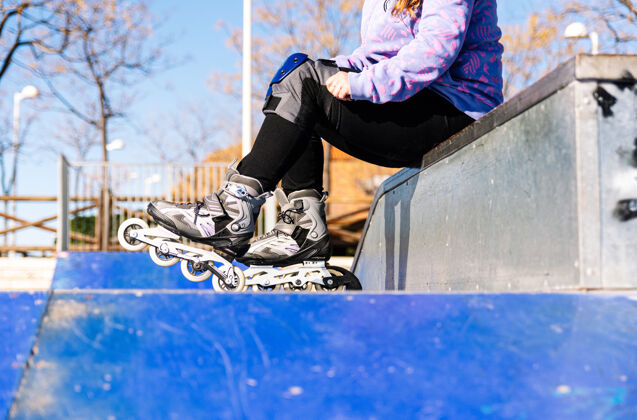 溜冰者一名女子在城市溜冰场上穿上溜冰鞋的特写镜头城市溜冰场滑冰概念女孩滚轴溜冰鞋女性
