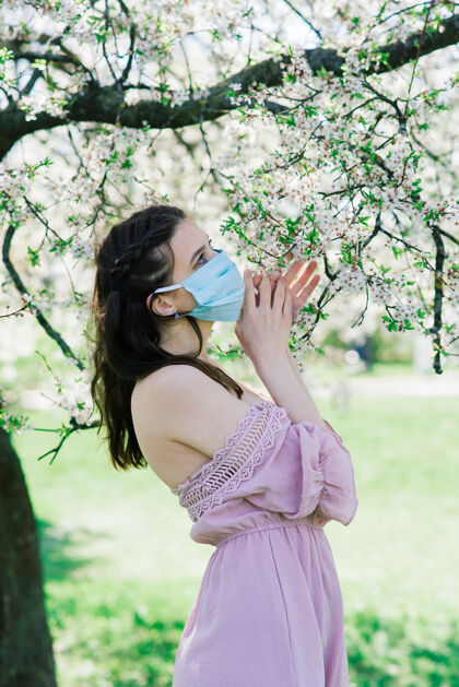 阅读新闻一位年轻的女性戴着医用面罩 以避免冠状病毒在公园花木之间传播冠状病毒街道疾病