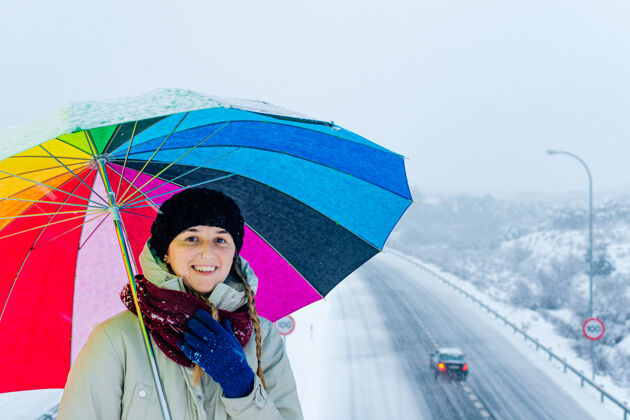 条件雪地公路上一个带着彩色雨伞的女人的画像驾驶轮胎降雪