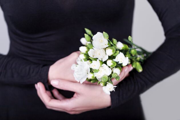 腰身美丽的女性手拿着一束白色康乃馨花手持裙子花