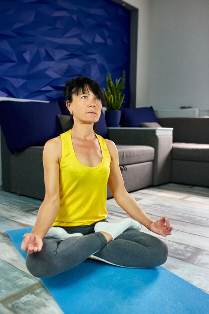 成人高级熟女 莲花坐在瑜伽垫上 晚上在客厅做伸展运动家健活方式理念冥想健康健身