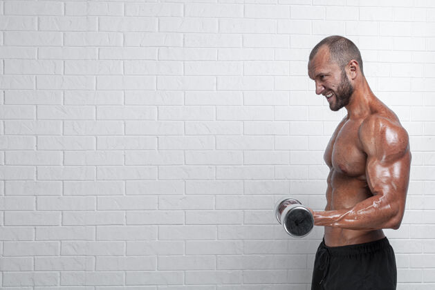 男人健美运动员在砖墙上用哑铃练习二头肌锻炼成人质量