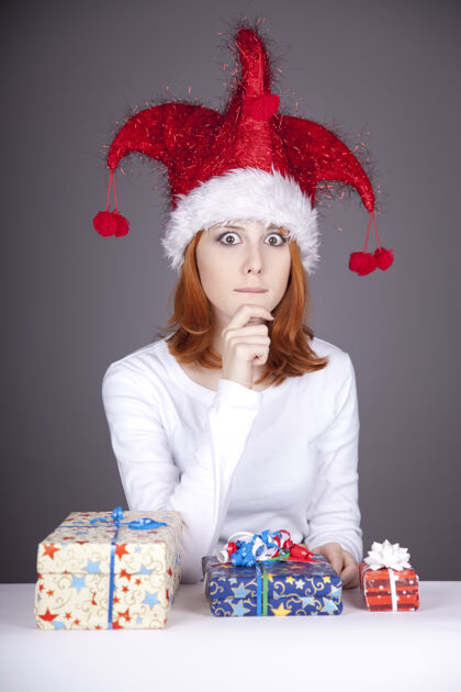 女性滑稽的红发女孩戴着圣诞帽 手里拿着礼品盒节日抱着服装