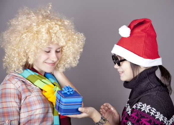 尼斯两个漂亮的女孩在圣诞节带着礼物帽子工作室射击服装女人甜蜜