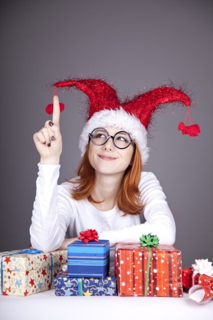 圣诞老人滑稽的红发女孩戴着圣诞帽 戴着带礼盒的眼镜圣诞节可爱桌子