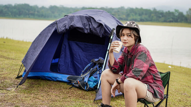 杯子年轻的亚洲女性在椅子上喝咖啡帐篷旅游者女性