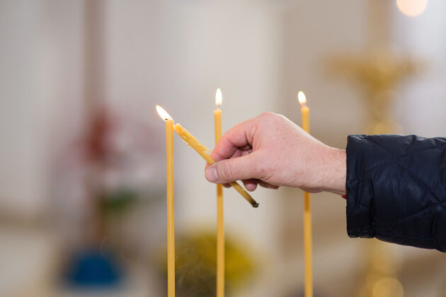 祈祷人的手在教堂里点燃蜡烛寺庙悲伤宗教