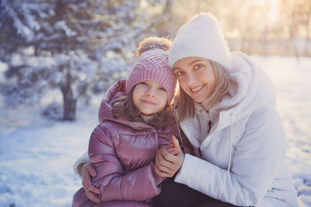女人妈妈和女儿在冬季公园玩得很开心成人快乐孩子