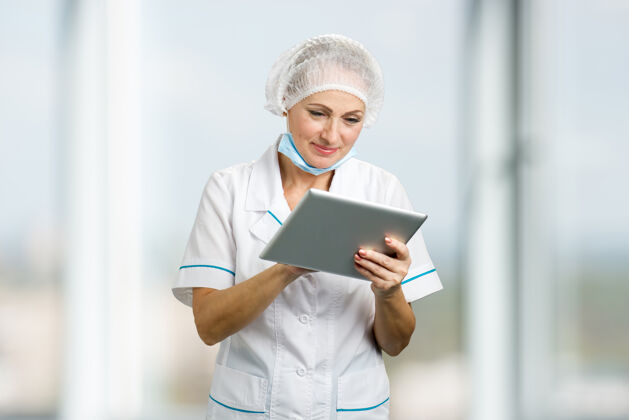 互联网美丽的女医生拿着电脑平板电脑成熟的女外科医生用数字平板电脑和微笑专家美丽职业