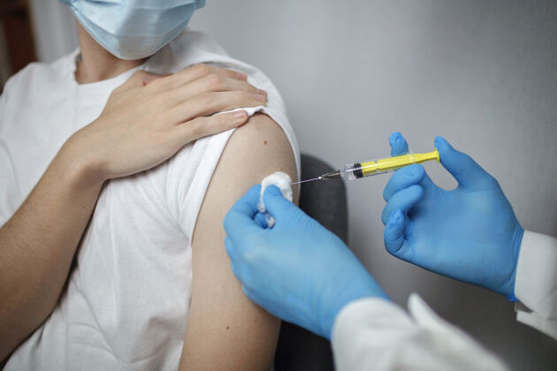手臂医生戴着医用口罩和手套 拿着装有冠状病毒疫苗的安瓿和注射器免疫疫苗治疗