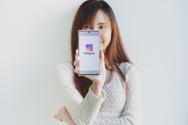 连接一位女士手拿三星Note10plus和instagram应用程序的登录屏幕手机技术评论