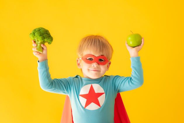 面具超级英雄小孩拿着花椰菜和苹果超级英雄梦想想象力