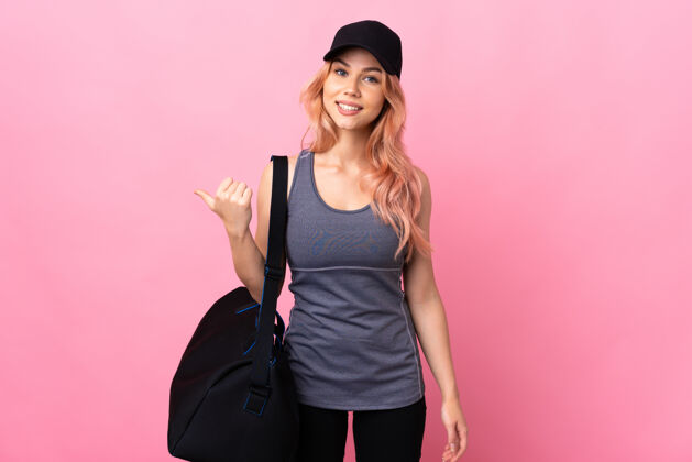 指十几岁的运动女子拿着运动包在孤立的背景上指着旁边展示一款产品右肖像护理