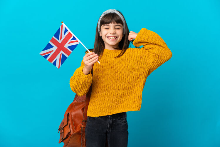 学生孤立在蓝色墙上学习英语的小女孩做了一个坚强的手势国旗大学英语