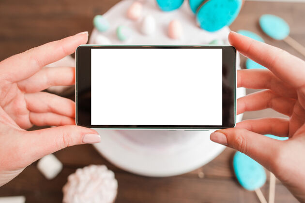 招待木质桌面上白色蛋糕的食品摄影带黑屏的智能手机手桌子木头