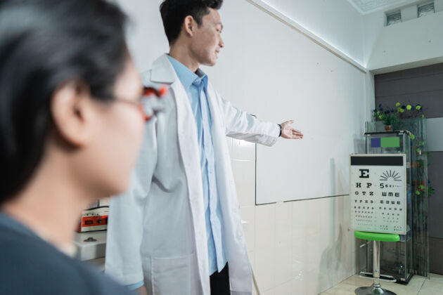 测试一位漂亮的女病人正在眼科诊所的一个房间里按照值班医生的指示做眼科检查光学亚洲人眼镜