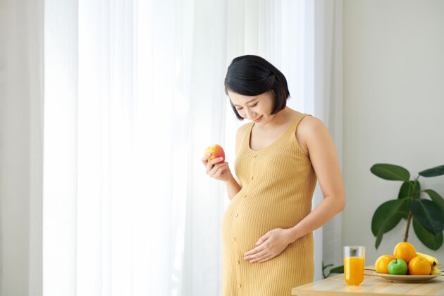 孕妇健康的饮食为我和我的宝宝美丽的孕妇吃水果沙拉和微笑女人室内中国