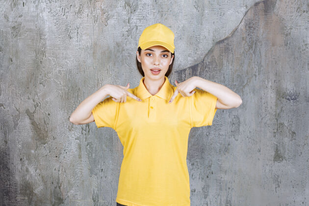 聪明身着黄色制服的女服务人员站在水泥墙上展示自己工人人体模特年轻人