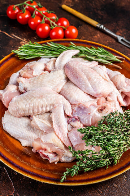 鸡翅把生鸡翅和百里香和迷迭香放在一个土盘子里切碎家禽营养健康