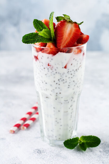 晚餐新鲜健康的奶昔酸奶 加上芝麻籽和草莓 放在一个玻璃烧杯里 靠在灰色的混凝土表面生的乳制品薄荷