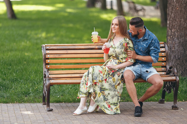 女性在阳光明媚的夏日 一对年轻时尚的情侣坐在长椅上 在城市公园里休息 喝着饮料男朋友休息姿势