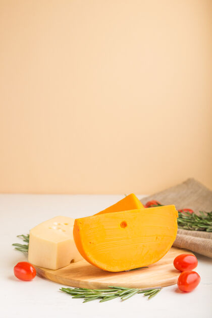 番茄各种类型的奶酪 迷迭香和西红柿放在木板上 表面是白色和橙色 亚麻织物蔬菜组菜肴