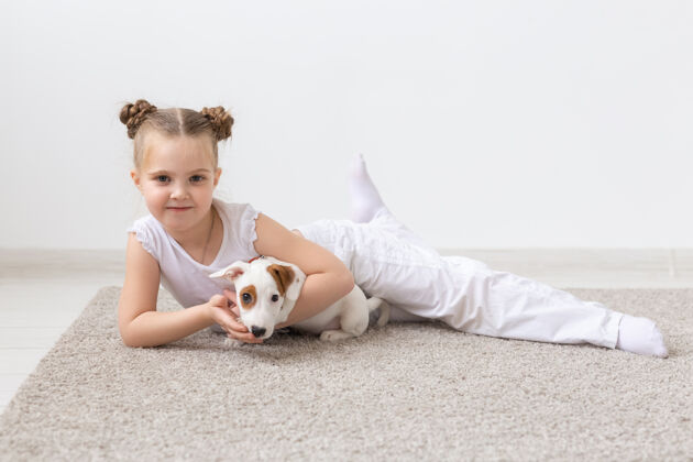 动物小时候的宠物和狗的概念小女孩摆在地板上与小狗梗狗姿势