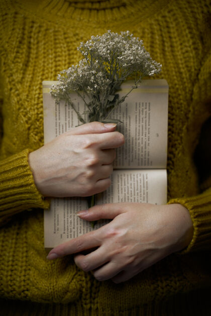 优雅穿毛衣的女孩正拿着书和花束打开纸书和野花在怀抱的女人温暖的芥末色针织毛衣浪漫的概念爱文学女性