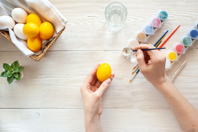顶视图给鸡蛋着色那个女孩在黄色的鸡蛋上画银色的图案自制华丽绘画