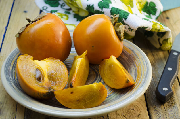 产品成熟的柿子放在木桌上的盘子里美味卡路里沙漠