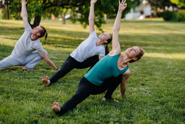 快乐一群人在日落时分在公园里做瑜伽健康的生活方式 冥想和健康平静草地冥想