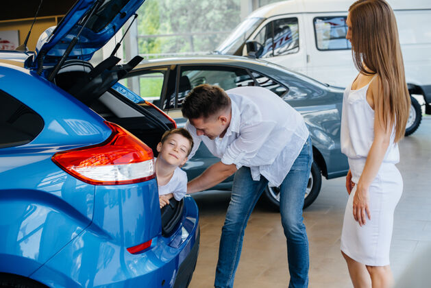汽车展厅一个小男孩坐在后备箱里 他的父母在选新车客户检查汽车