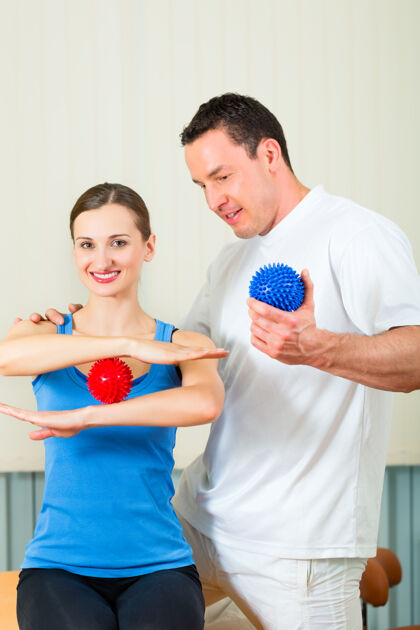 物理女患者在理疗室和她的治疗师做体育锻炼 她们用的是按摩球物理治疗师医生球