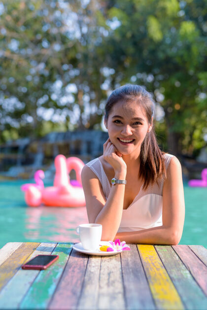 泰国年轻美丽的亚洲女游客在湖边户外放松的画像公园下巴东南