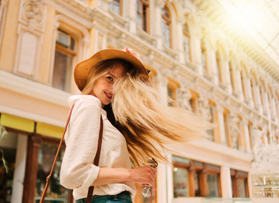女人一个年轻的金发女游客戴着帽子的城市建筑肖像街头城市探索