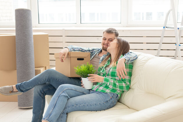 年轻积极恋爱的年轻夫妇夫妻正坐在新客厅的沙发上购买男朋友男人