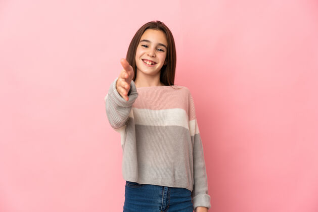 自然小女孩孤零零地站在粉红色的墙上 为成交而握手小童年人