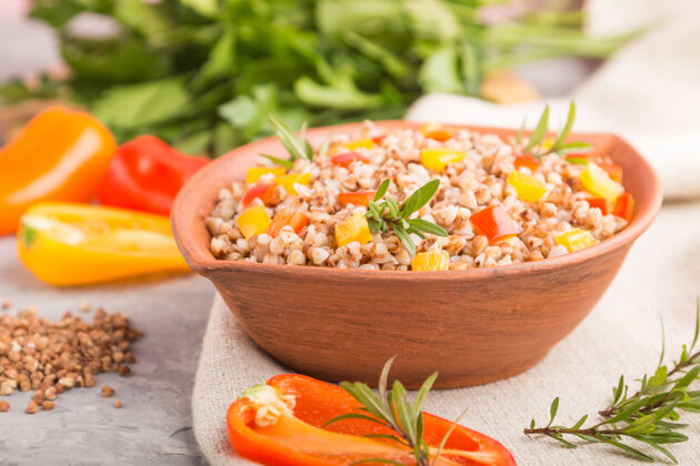 素食者荞麦粥和蔬菜在一个灰色的混凝土表面和亚麻织物粘土碗侧视图 选择重点 特写健康自然草药