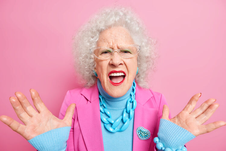 老奶奶失望的老卷发女人举起手掌大声地表示消极的情绪穿着优雅的衣服红色唇膏和化妆品抱怨严重项链