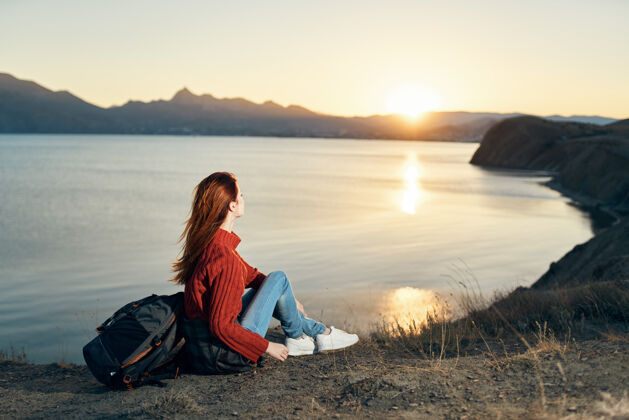 和平一个穿着毛衣的旅行者坐在海边的山上看日落旅游满足日落