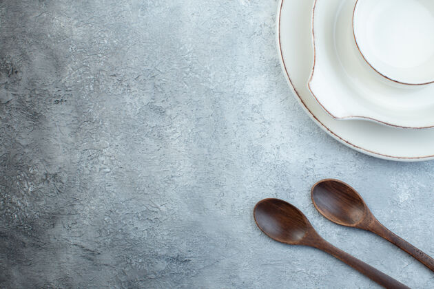 壁板优雅的白色餐具 左侧木质勺子 灰色表面 空间宽敞晚餐器皿左