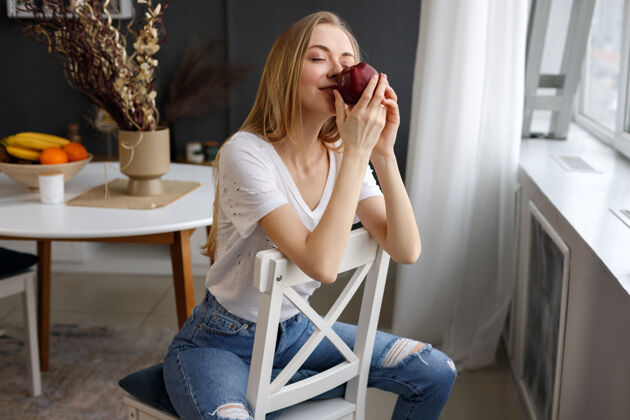 抱着健康的女人坐在椅子上闻着红苹果水果女人新鲜