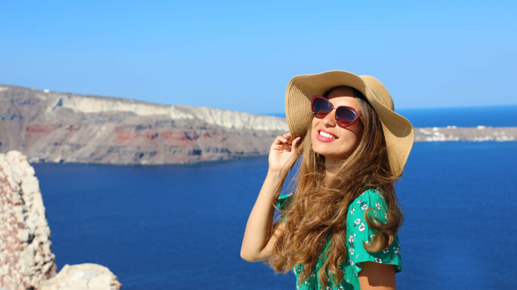 帽子希腊圣托里尼 戴着帽子和太阳镜的女人在享受阳光海圣托里尼希腊语