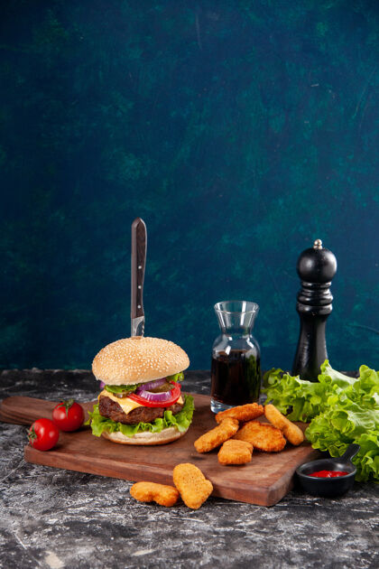 肉三明治特写镜头刀在美味的肉三明治和鸡块西红柿干胡椒木板酱番茄酱在深蓝色的表面干食物番茄酱
