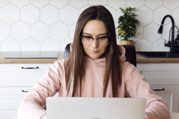计算机戴眼镜的女自由职业者专注于笔记本电脑员工房屋室内植物