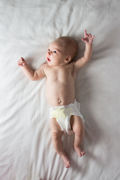 宝贝穿着尿布的女婴躺在白色毯子上可爱困倦美丽