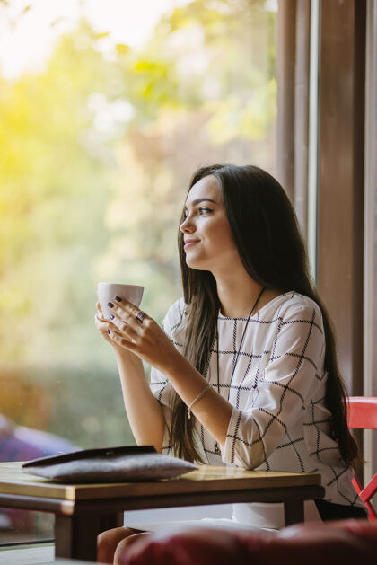 咖啡年轻漂亮的黑发女郎坐在咖啡馆里喝茶坐着会议黑发
