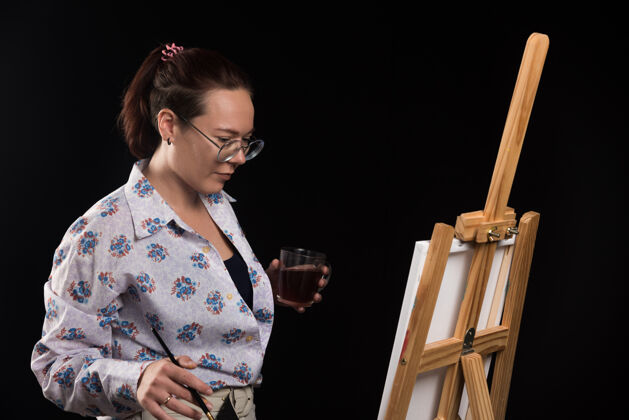 女性女画家拿着画笔 看着黑色的画布画布图片艺术家